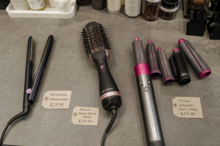 Three hair styling tools displayed with price tags: Remington Straightener $29.99, Revlon Round Brush Dryer $39.99, and Dyson Airwrap Multi-Styler $59.99